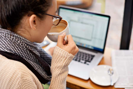 Sipping coffee while enjoying free wifi. Cropped shot of an attractive young woman surfing the net...