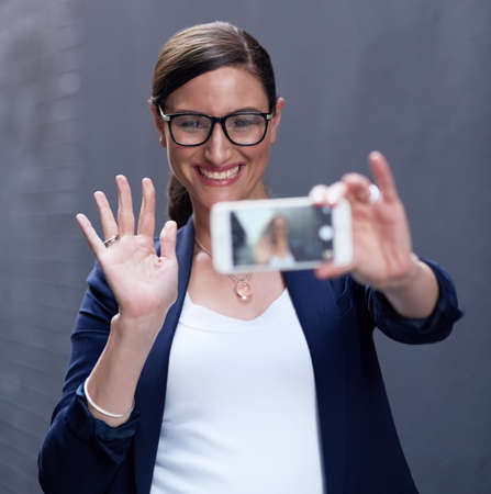 Hello social media, hello world. Shot of a happy businesswoman taking a fun selfie with her...