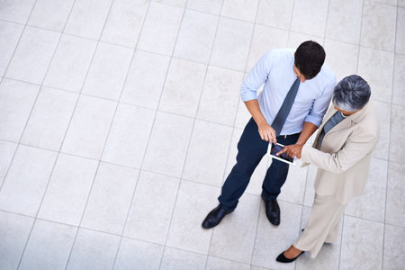 Successful professionals understand the importance of networking. High angle portrait of a professional man and woman using a tablet.の写真素材