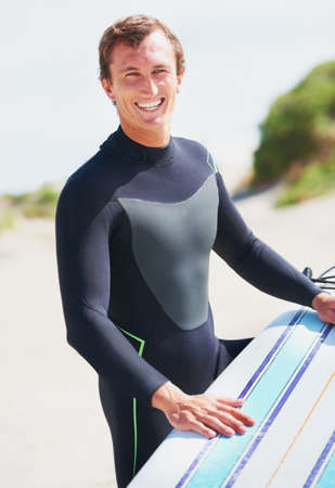 Ready to hit the waves. A surfer resting his board on his leg getting ready for a surf session.
