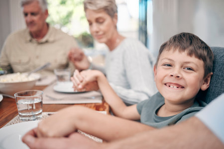 I wished for a happy family and it came true. Shot of a family holding hands in prayer before having a meal together at home.の写真素材