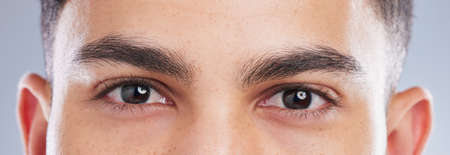 I see you too. Shot of an handsome young mans eyes against a studio background.の写真素材