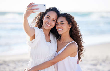 How lucky I am to have her in my life. Shot of two young women taking selfies at the beach.の写真素材