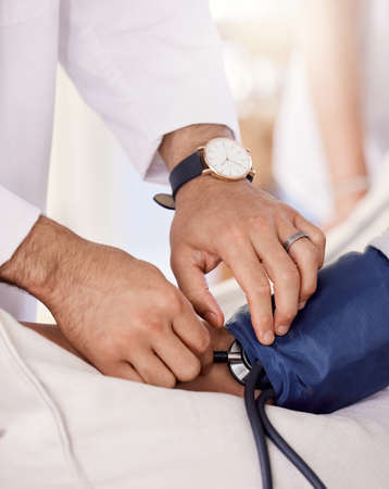 Let me check you blood pressure. Shot of a male doctor examining a senior patient with a blood...
