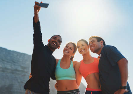 Take this for some fitness inspiration. Shot of a group of friends taking a selfie while out for a workout.の写真素材