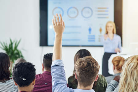 Raise your hands for learning opportunites. Shot of a group of businesspeople raising their hands in a class.の写真素材