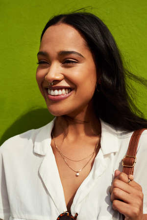 Living my best life. Cropped shot of an attractive young woman standing alone against a green...