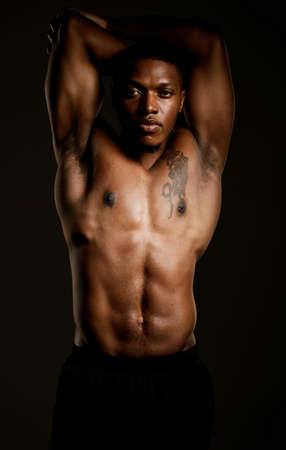 All muscle, all man. Studio shot of a fit young man posing against a black background.