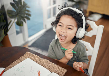 Im in the zone. Shot of an adorable little boy wearing headphones while drawing at home.の写真素材
