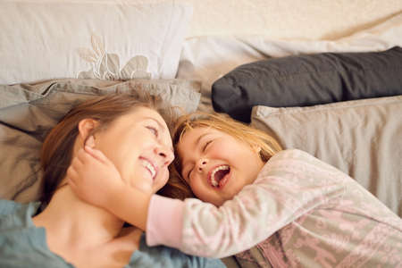 Here comes the tickle monster. Shot of a mother and her little girl lying in bed together at home.