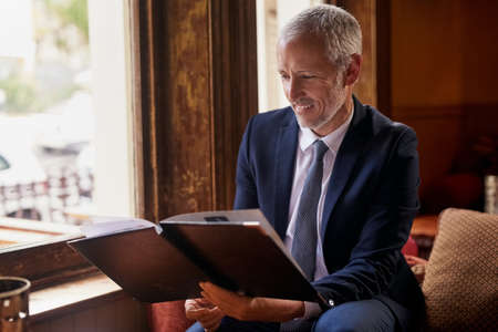 Whats on the menu for today. Shot of a well-dressed mature man reading a menu in a cafe after work.