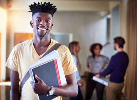 Knowledge is the key to unlock opportunity. Portrait of a university student standing in a corridor at campus.の写真素材