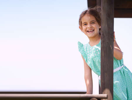 She love playing outside. Portrait of a little girl playing on a jungle gym on a sunny day.の写真素材