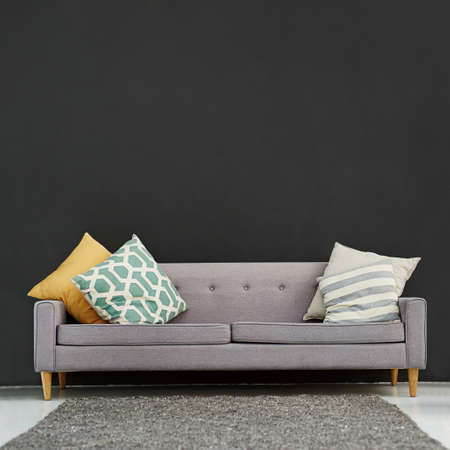 Functional and stylish for your office or home. Shot of a gray sofa with cushions against a black background.の写真素材