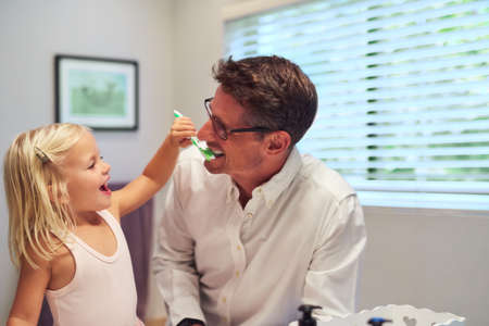 This is how youre supposed to brush, Dad. Shot of a little girl helping her father brush his teeth...