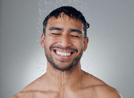 Happy to be clean. Shot of a young man taking a shower against a grey background.の写真素材