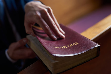 Finding comfort in the good book. Cropped shot of a man opening a bible while sitting in a pew at...