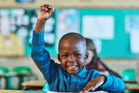 I have a question teacher. Cropped shot of an elementary school boy hand raised in the classroom.の写真素材