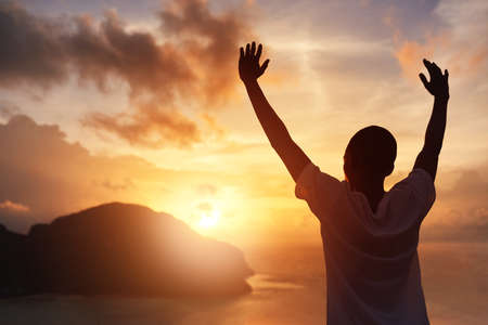 Embracing summer with open arms. Rearview shot of a young tourist raising his arms against a sunset...