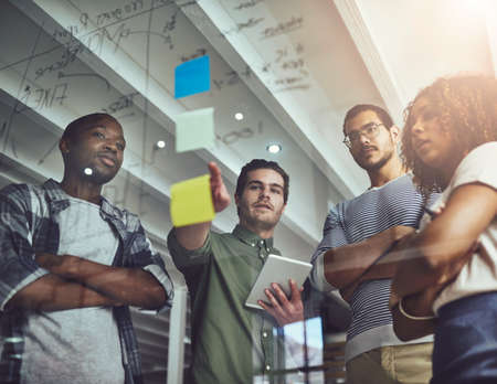 I think thats what we need to focus on. Low angle shot of a group of young designers planning on a glass board.の写真素材