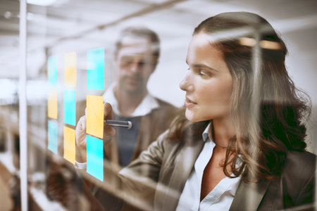 Coming up with a strategy is step one. Cropped shot of two businesspeople working on a glass wipe...