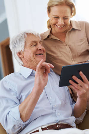 And thats how the movie ended.... Shot of a senior man sharing a joke on his digital tablet with his wife.の写真素材