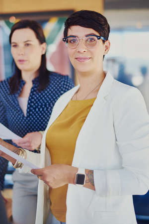 Success is certain. Cropped portrait of a businesswoman standing in the office with a colleague in the background.の写真素材