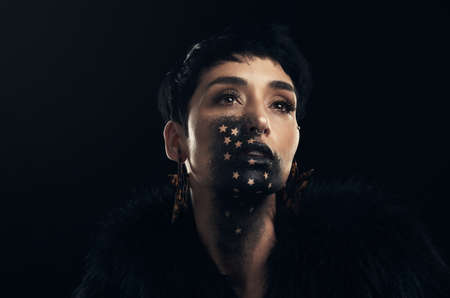 Beauty shinning like a candle in the dark. Studio shot of a young woman posing with paint on her...