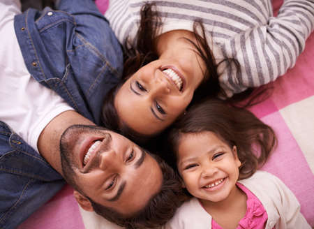 The strongest family bonds. High angle portrait of a happy young family lying on their backs at...
