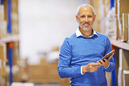 Your order was shipped yesterday. Portrait of a mature man working inside in a distribution warehouse.の写真素材