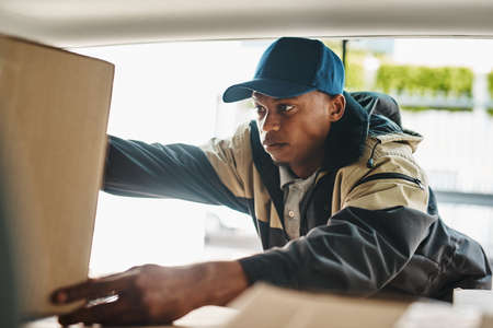 Hitting the road with a new batch of deliveries. Shot of a courier sorting boxes in a delivery van.の写真素材