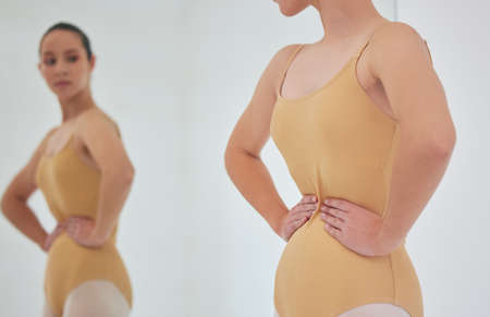 Im warping here. Shot of a young ballet dancer inspecting her figure in a mirror during a rehearsal.