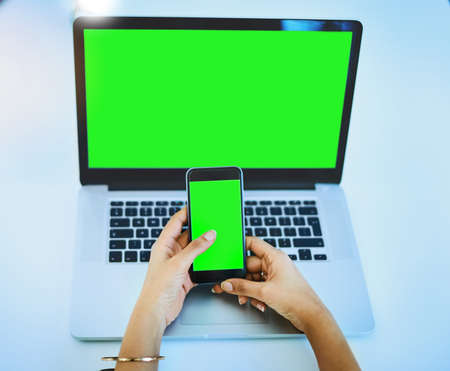 Technology always plays a hand in business. Shot of an unrecognizable businesswoman using her cellphone and laptop at her office desk at work.の写真素材