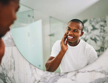 Hey there handsome. Shot of a young man going through his morning routine in the bathroom at home.の写真素材