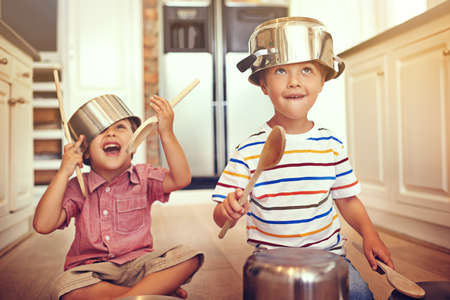 Lets get this party started. Two young boys sitting on the kitchen floor playing with pots and pans.の写真素材