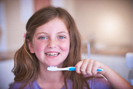 Making sure my pearly whites stay pearly. Cropped shot of a little girl brushing her teeth.の写真素材