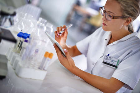 Recording her data for further analysis. A young scientist working on a research project using a...