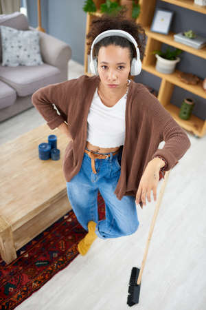 Im waiting for the next song to start before cleaning again. Shot of a woman wearing headphones...