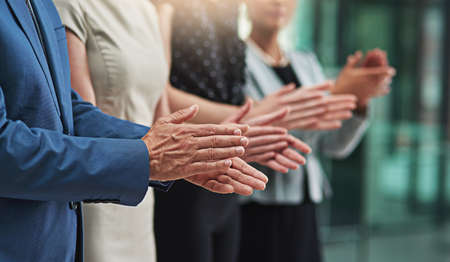 That was an outstanding job. Cropped shot of a group of unrecognisable businesspeople applauding together in an office.の写真素材