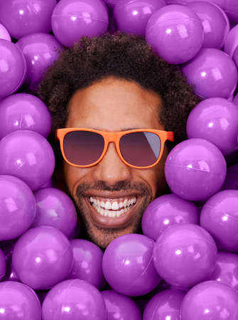 Looking cool and crazy. A young black mans face amongst purple pit balls.の写真素材