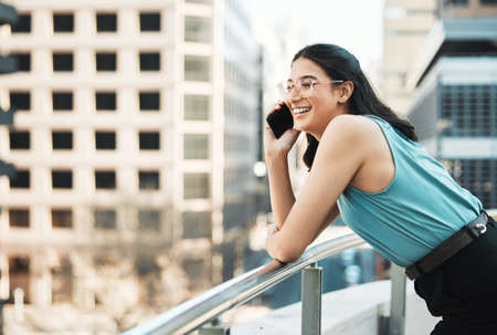 Staying confident and relaxed gets the job done. Shot of an attractive young businesswoman standing alone outside and using her cellphone.の写真素材