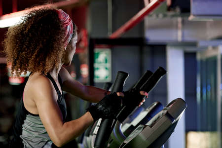 Time to step up this workout. Shot of a young woman working out with a stepping machine at the gym.