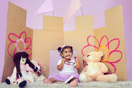 I liked that story. Can I have another one. Shot of an adorable little girl reading a book surrounded by her toys.の写真素材