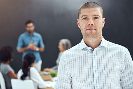 Its a serious meeting. Portrait of a businessman standing in the boardroom while a colleague gives a...