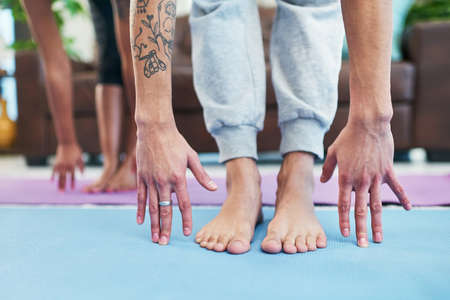 Yoga helped us to find balance in our relationship. Cropped shot of an unrecognizable couple practising yoga at home.の写真素材