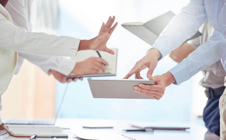 It seems to be a busy day in the office. Shot of a group of unrecognizable businesspeople working in...