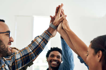 Teamwork for the win. Shot of a group of colleagues giving each other a high five in a modern...