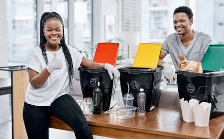 Saving the earth starts at home. Shot of a young couple recycling their trash at home.の写真素材