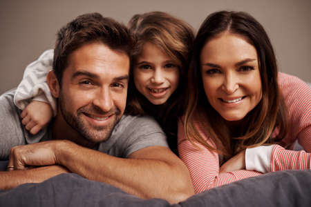 Morning cuddles. Portrait of a happy family lying on a bed.