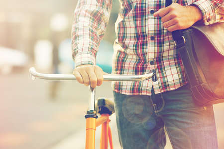 Keeping his carbon footprint as low as possible. Cropped shot of a man pushing his bicycle in the city.の写真素材